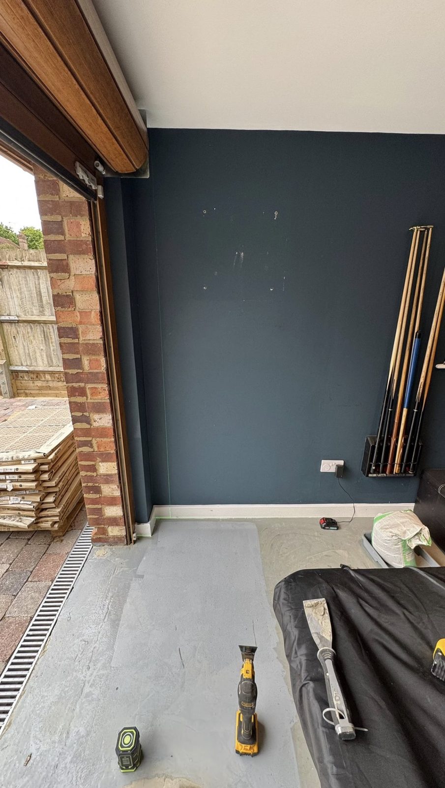 The empty navy wall before installation, with marks from previous fixings